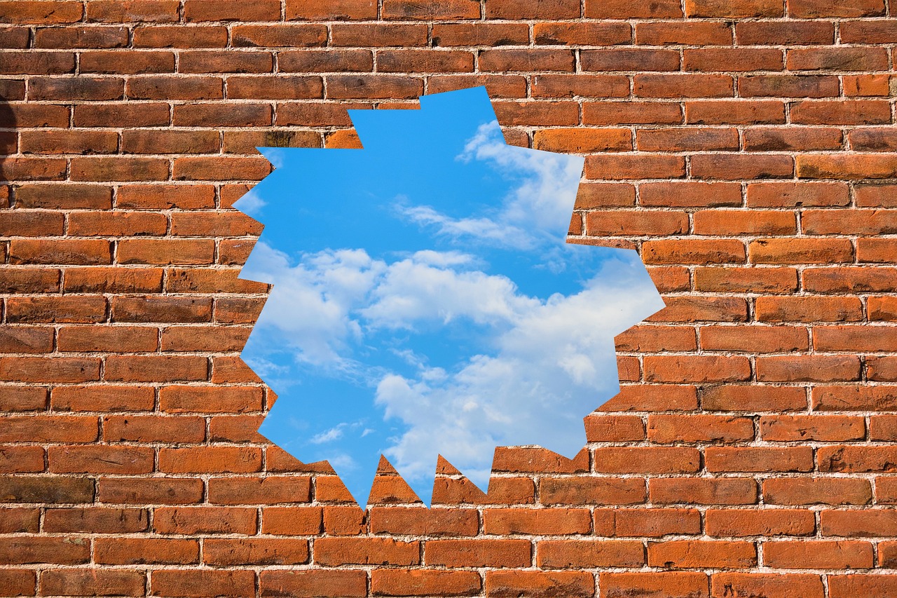 brick wall with hole in it showing blue sky trinity esoterics