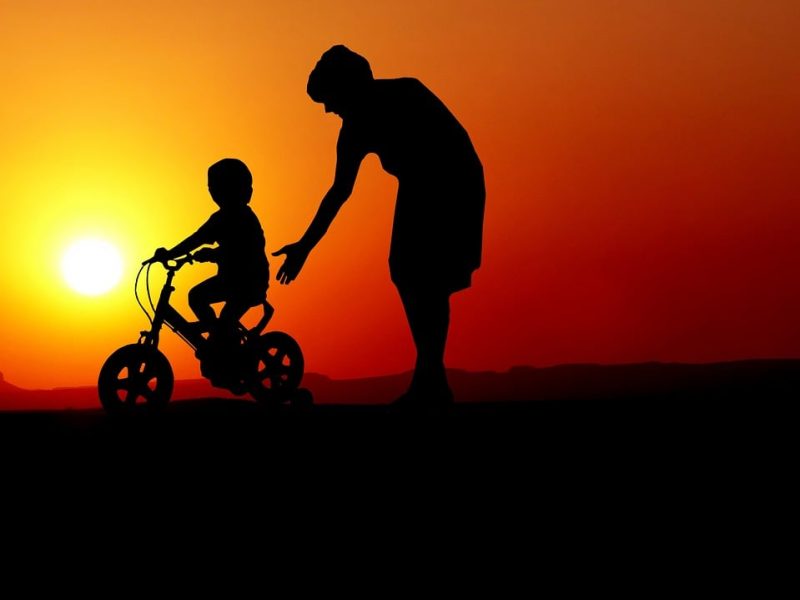 adult teaching child to ride bike trinity esoterics