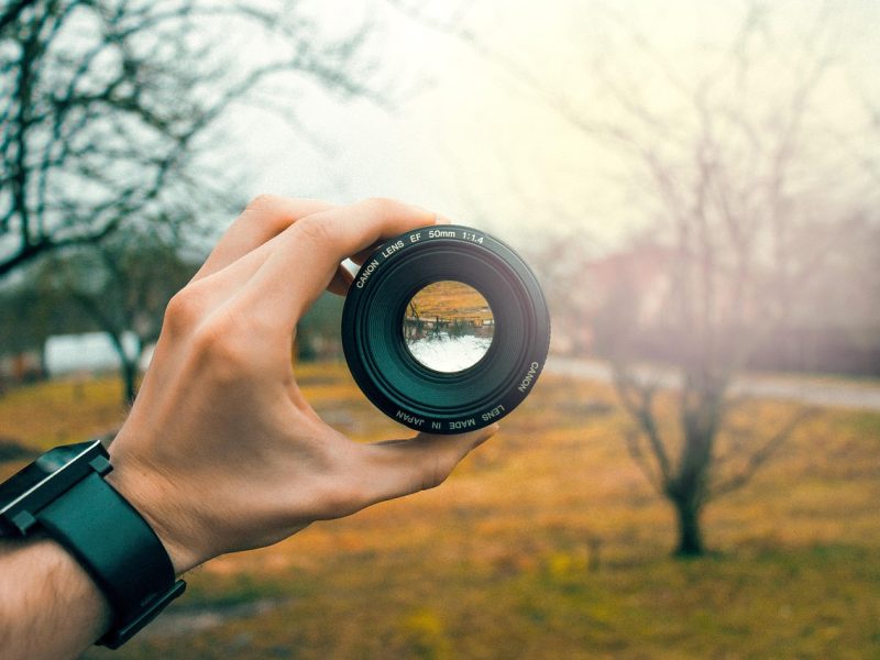 person holding up camera lens trinity esoterics