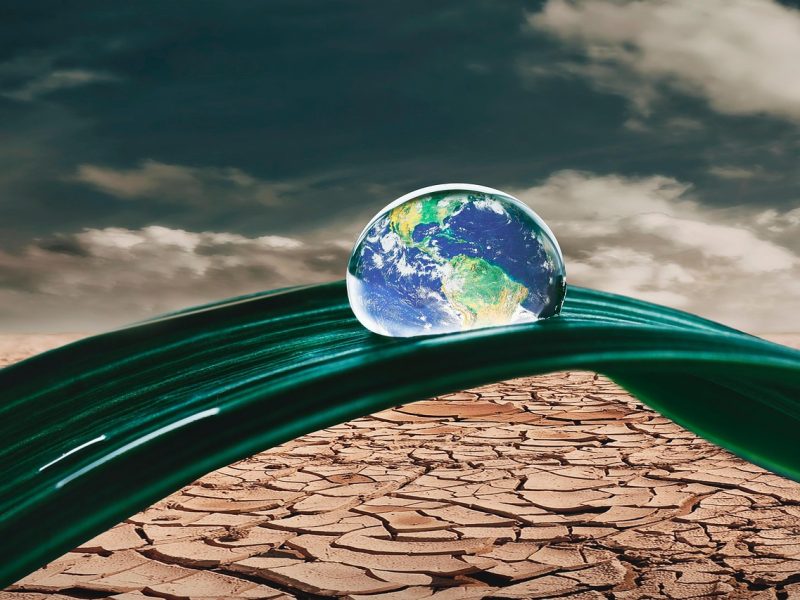 water droplet that looks like the earth above parched land trinity esoterics