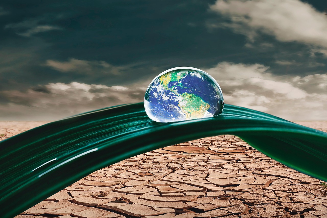 water droplet that looks like the earth above parched land trinity esoterics