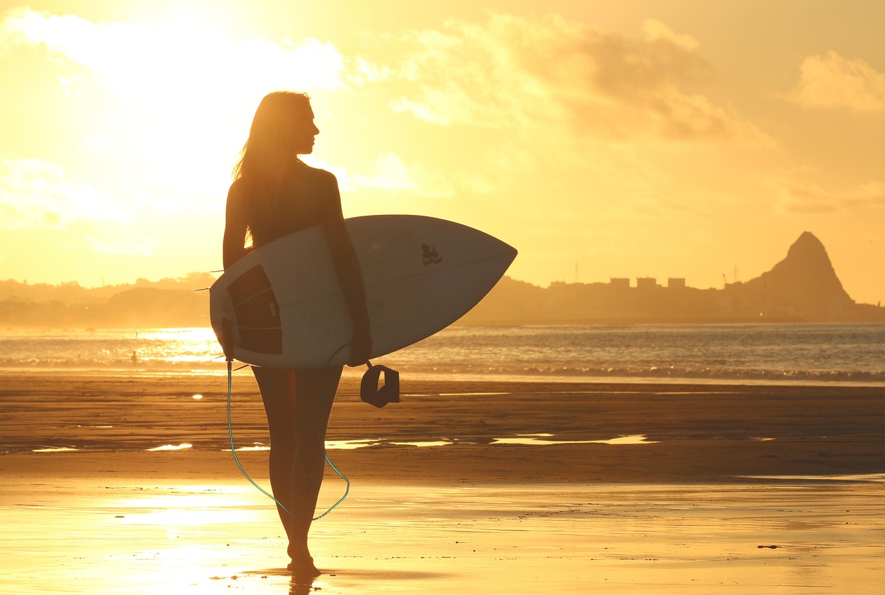 surfer walking towards ocean with surf board trinity esoterics